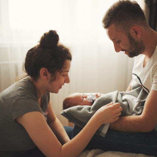 mother and father with newborn baby at home